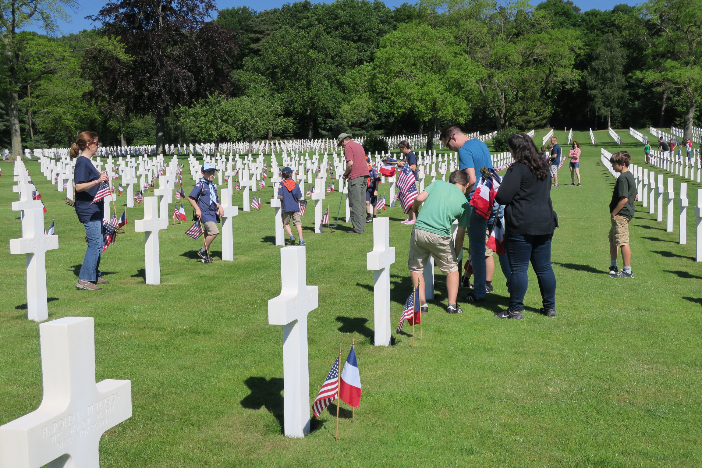 Men, women and children all work to place flags. 