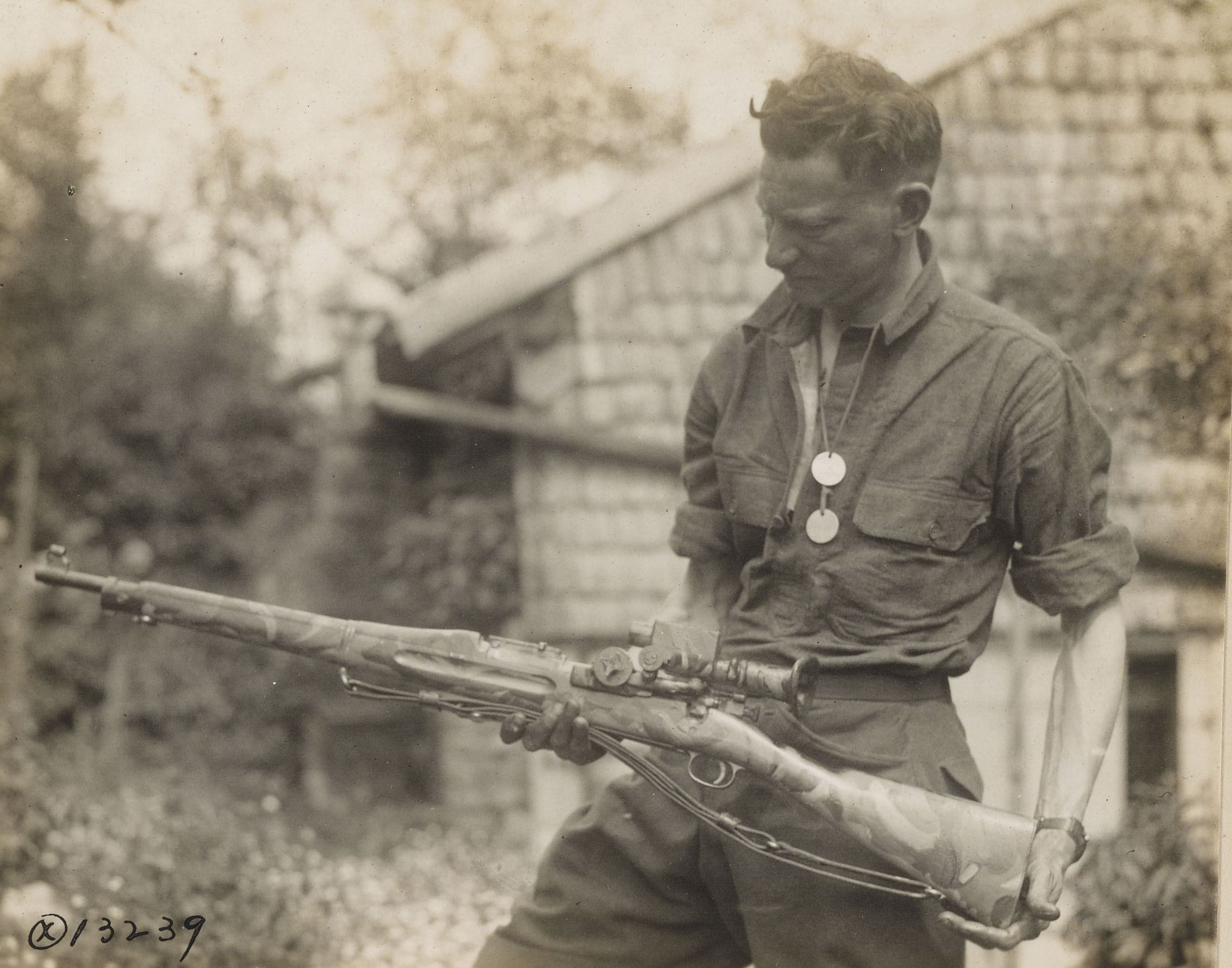 Historic photo shows man with rifle in hand. 