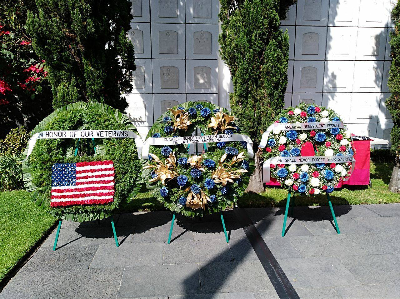 Three large floral wreaths on stands in front of the crypt. 