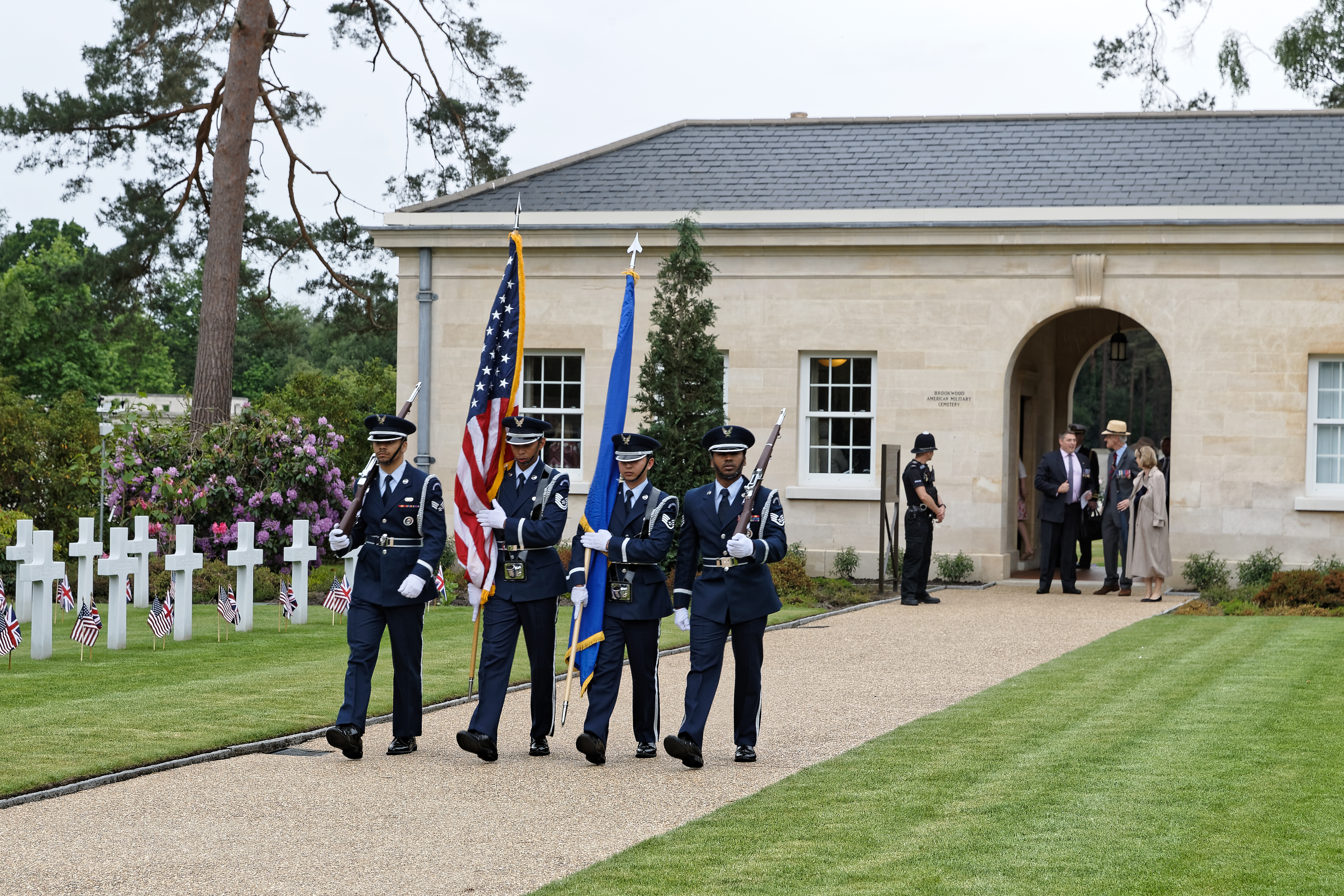 Men in uniform carry a flag or a rifle as part of the Honor Guard.