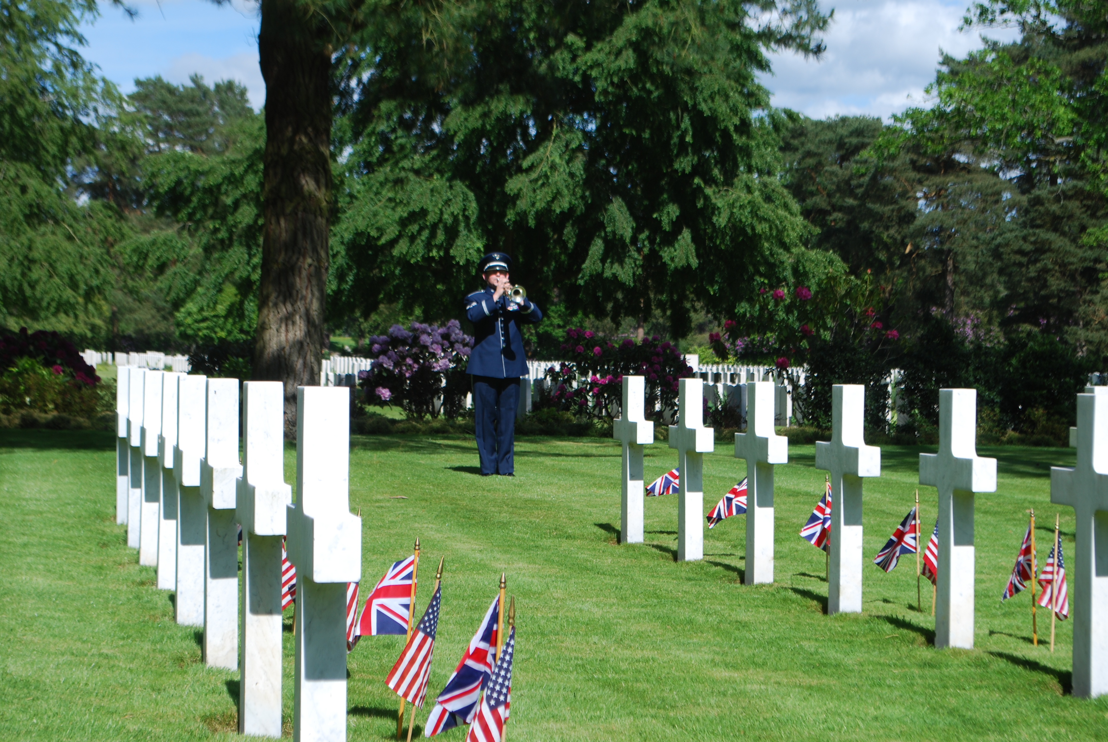 A bugler stands amongst the headstones and plays. 