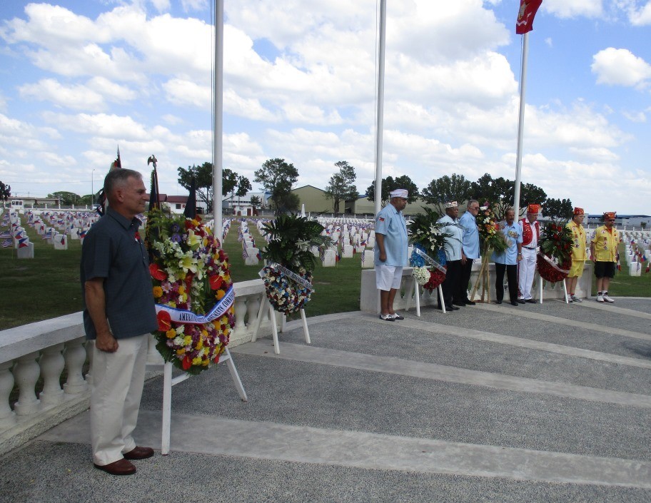 Ceremony participants stand next to the floral wreaths they laid. 