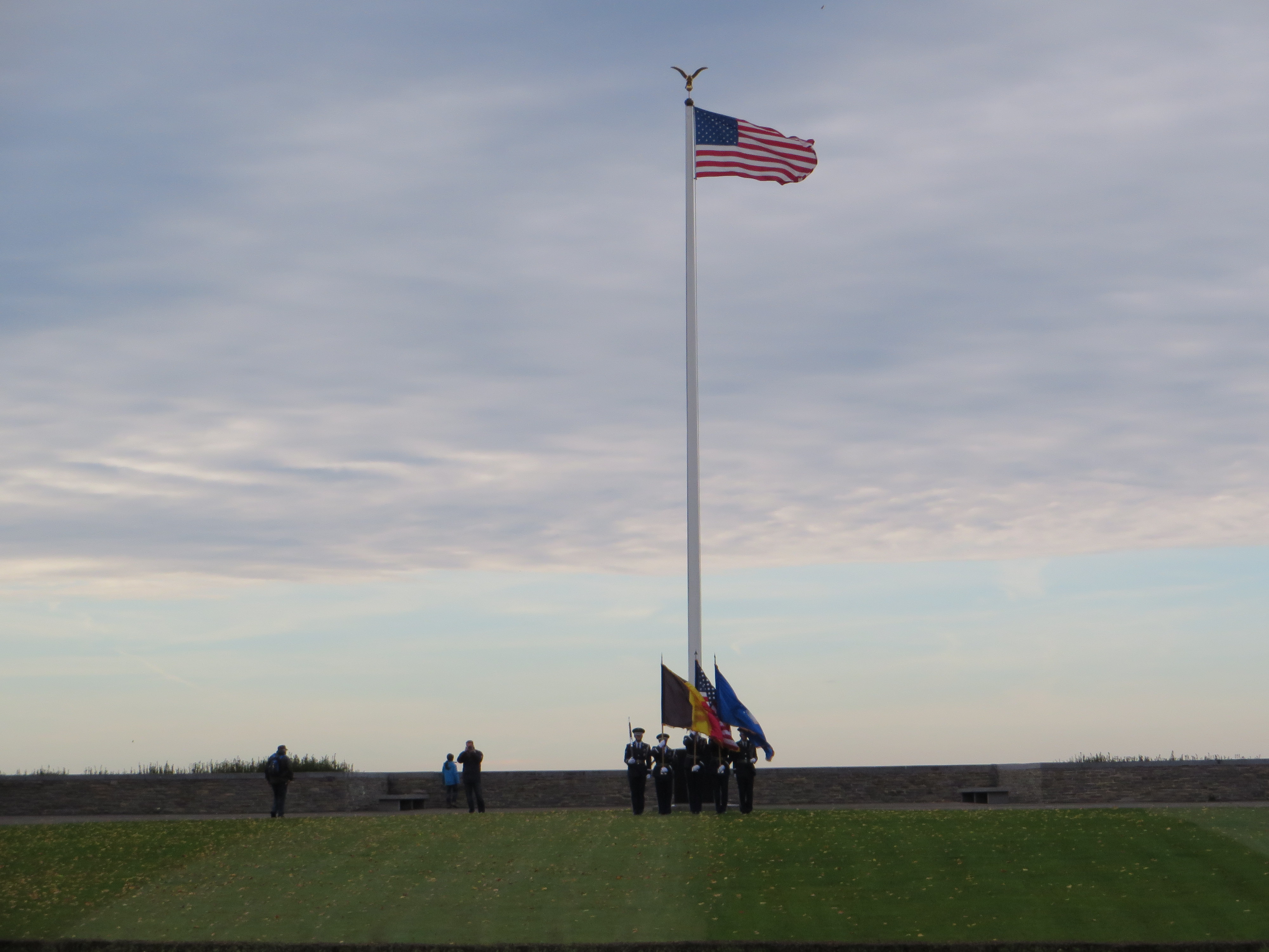 In the distance, an honor guard is seen at the flag pole. 