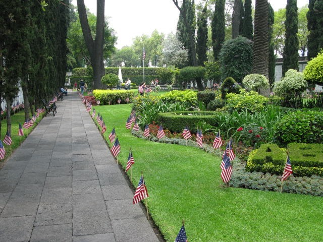 American flags line the pathway and floral beds at the cemetery. 