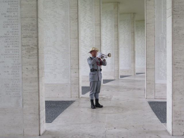 A man in uniform plays the bugle amidst the Walls of the Missing.