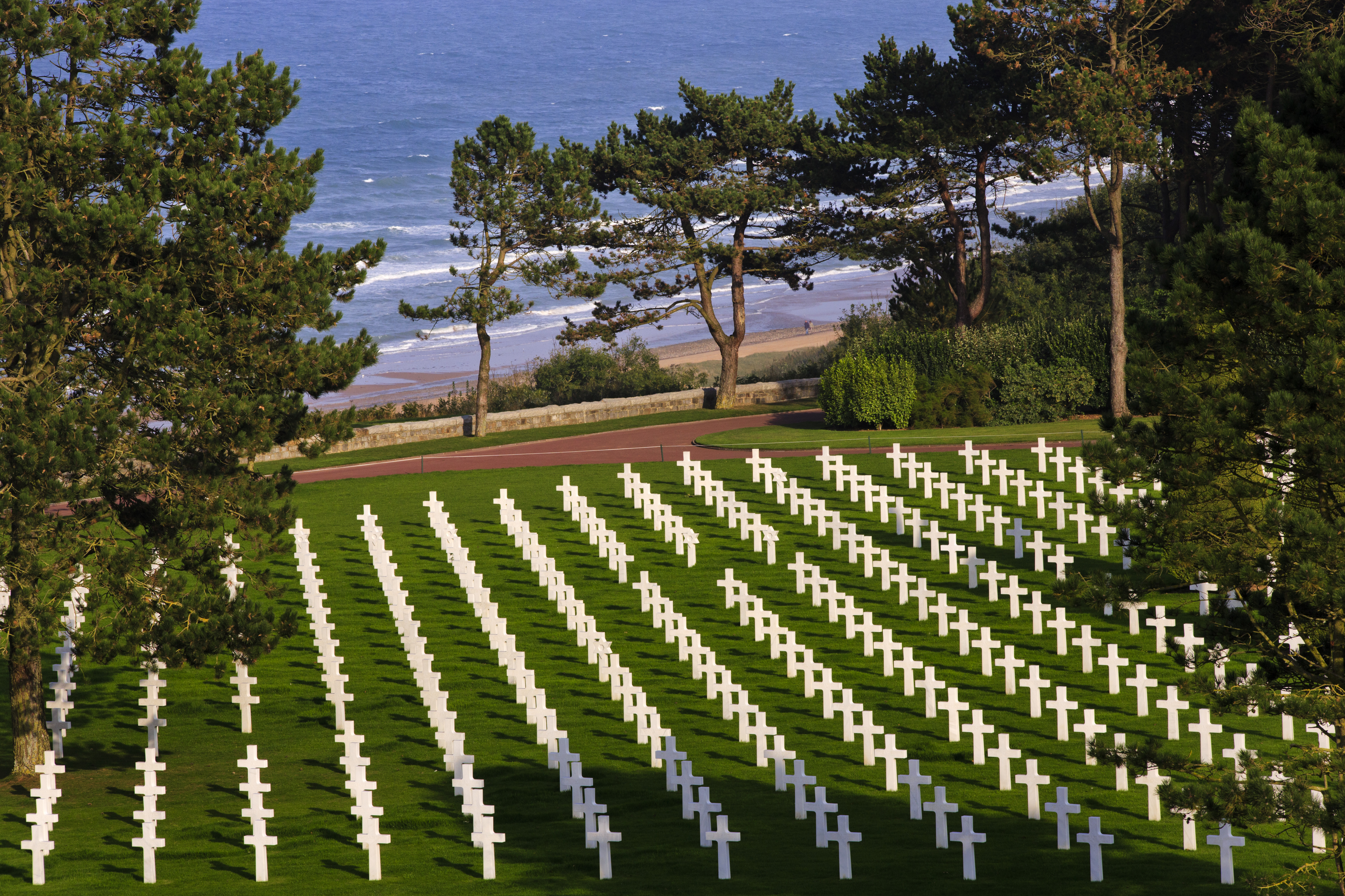 Rows of marble headstones dot the landscape with the English Channel in the background.