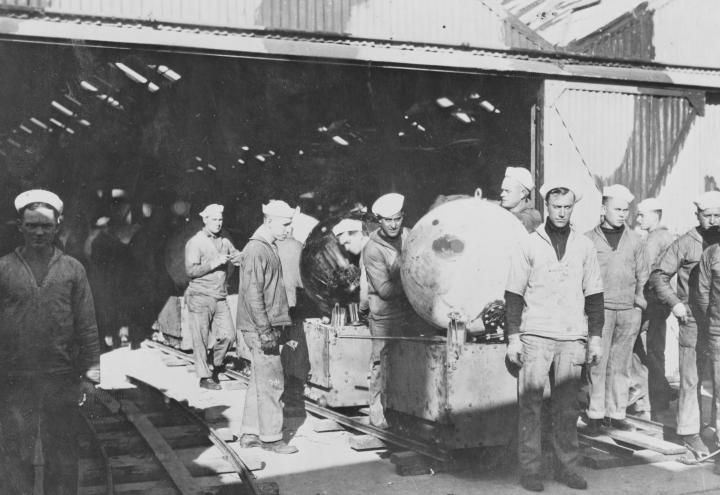 Historic photo shows men in uniform assembling mines. 
