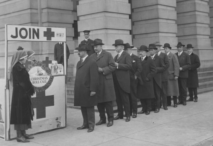 Historic photo shows lawmakers standing outside in line at Red Cross booth. 