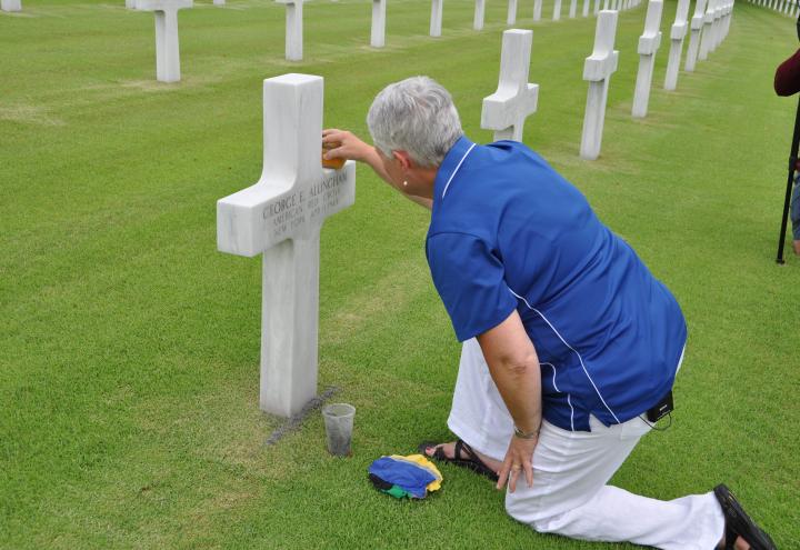 Touzel kneels on the ground as she takes a sponge to the headstone.