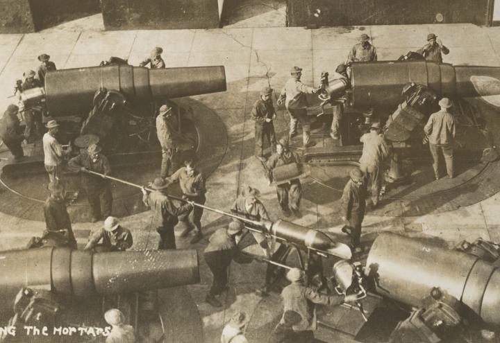 Historic photos shows men loading large mortars. 