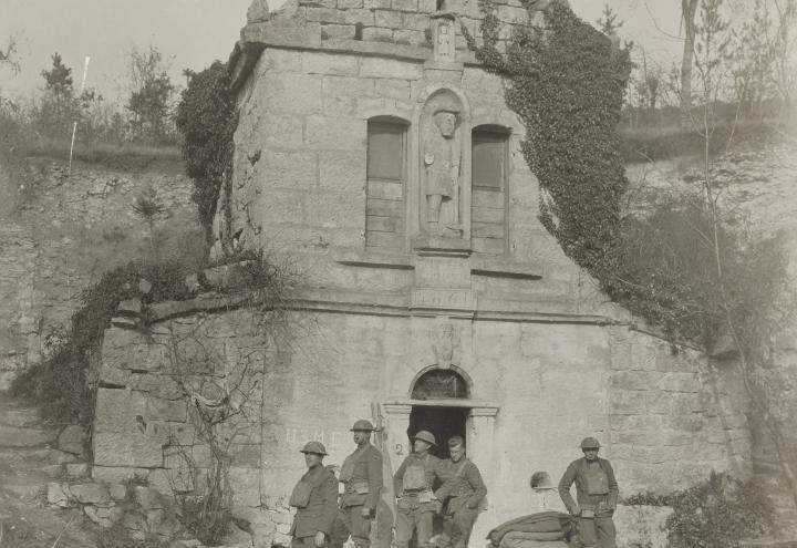 Historic photo shows soldiers standing in front of brick monument. 