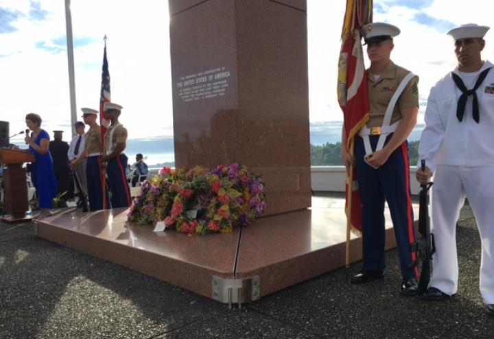 Three Marines and a sailor stand next to the granite memorial.