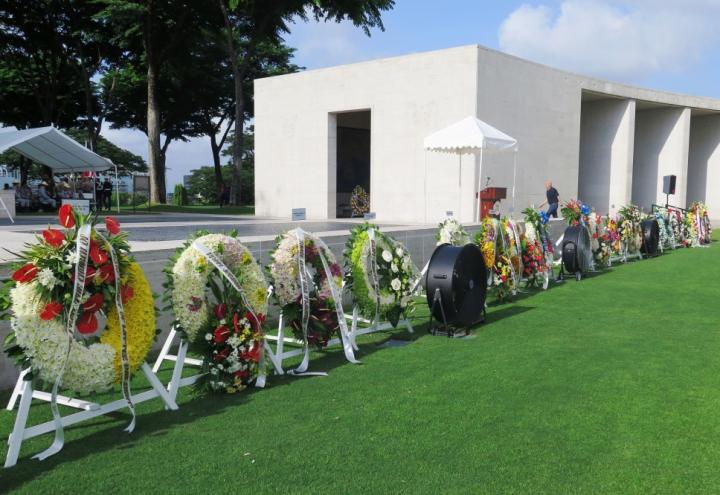 Floral wreaths on stands rest near the Walls of the Missing. 