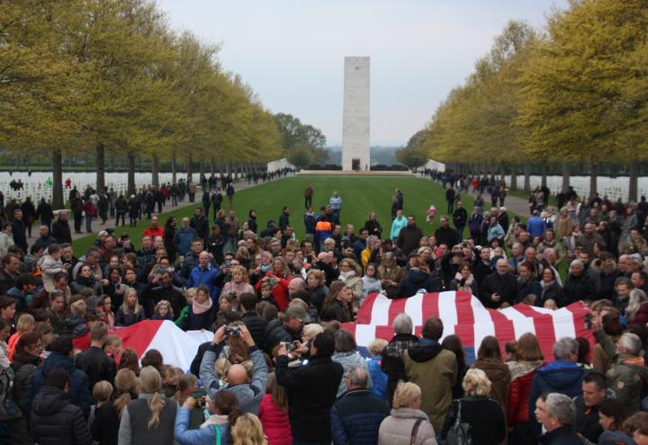 People gather around a large American flag. 