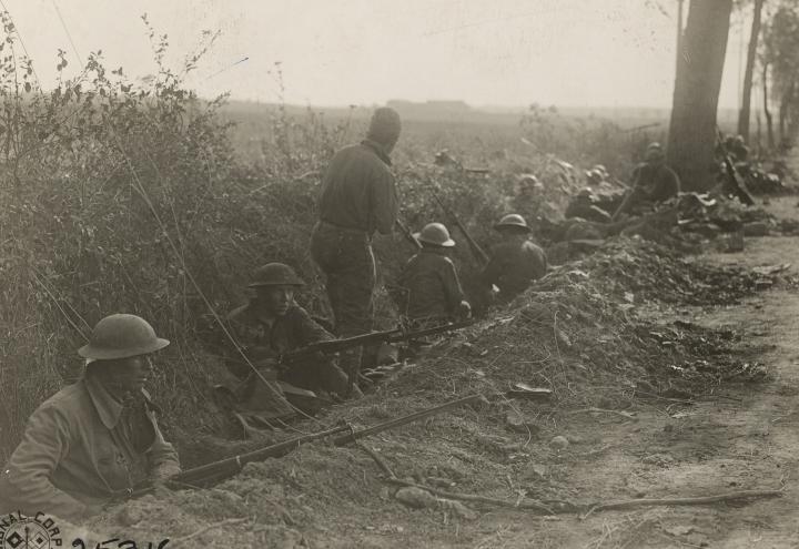 Historic photos show men in trench preparing to go over the top. 