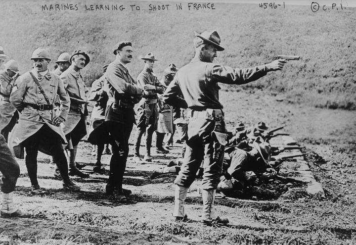 Historic photo showing Marine pointing hand gun, ready to fire. 
