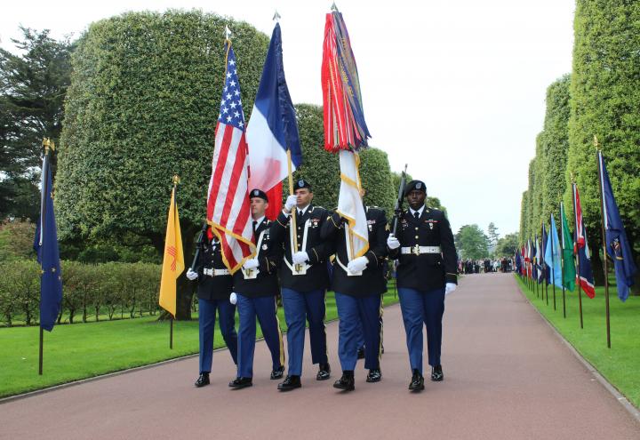 Men and a woman in uniform march in during the ceremony. 