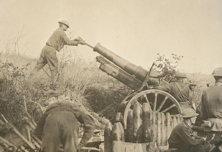 Historic photo shows man tamping down inside of howitzer.