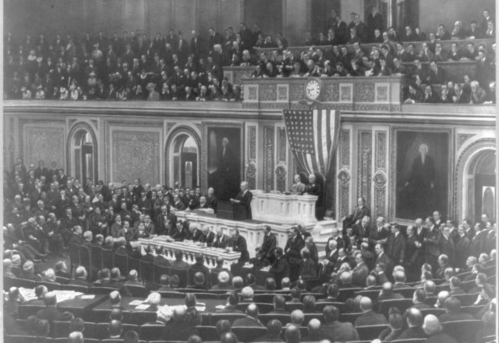 In historic image Wilson stands at podium and addresses Congress. 