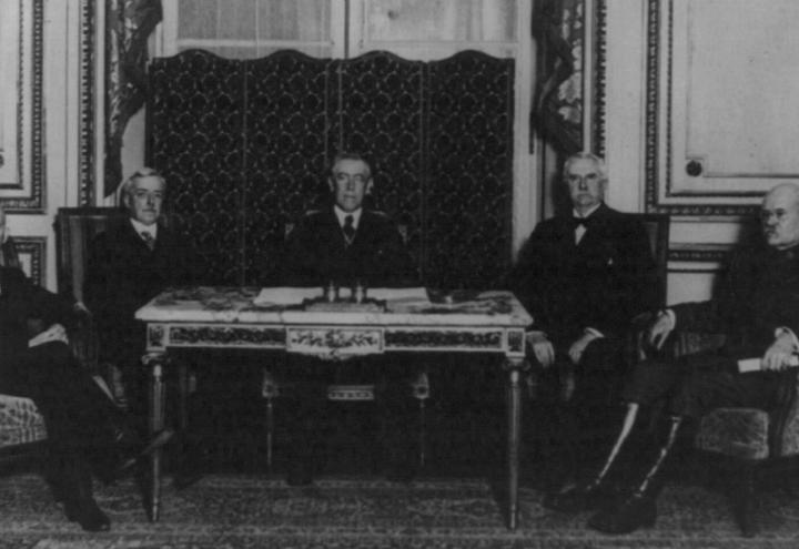 Historic photo showing men sitting at a table. 