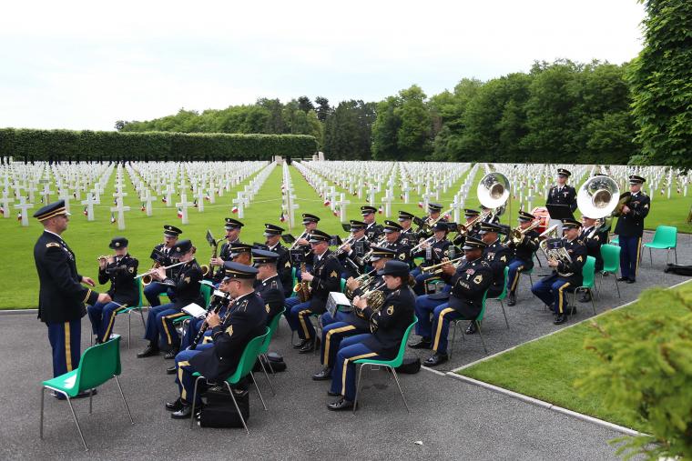 Men and women in uniform sit while they play their instruments. 