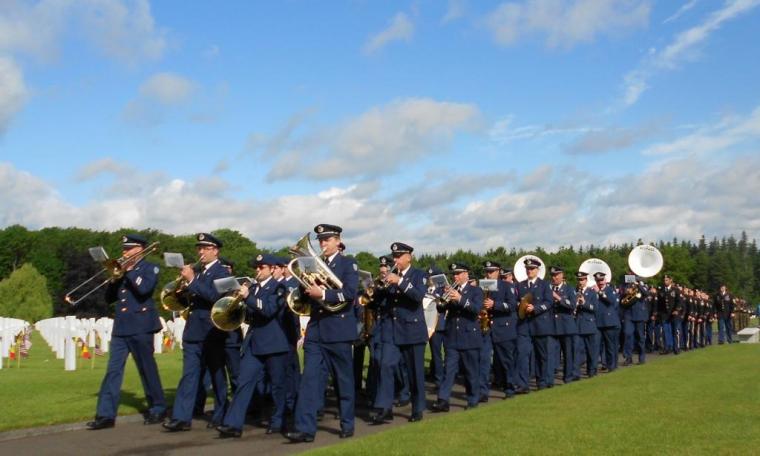 A military band in uniform marches with instruments. 