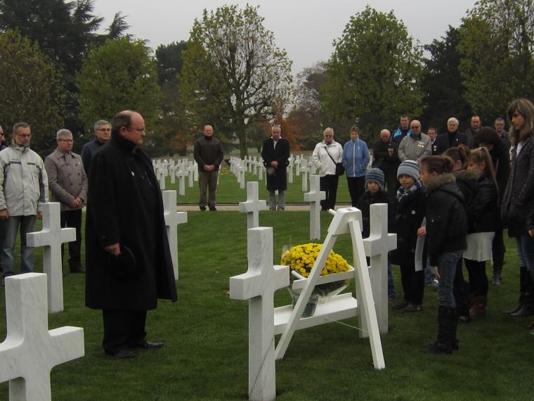 Flowers are laid at a headstone as people are gathered around the site at Somme American Cemetery.