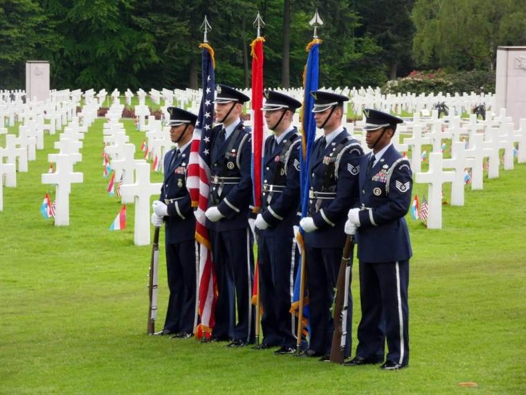 A U.S. Color Guard stands in front of headstones.
