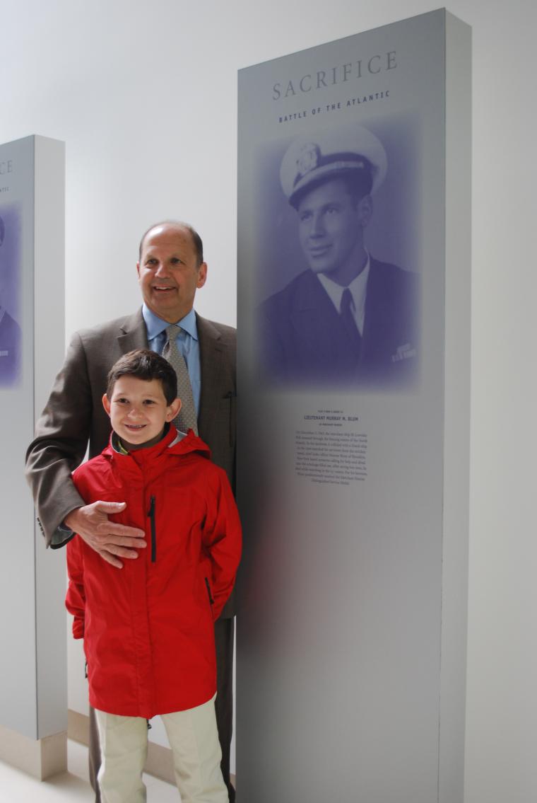 Blum family members stand in front of an exhibit panel. 