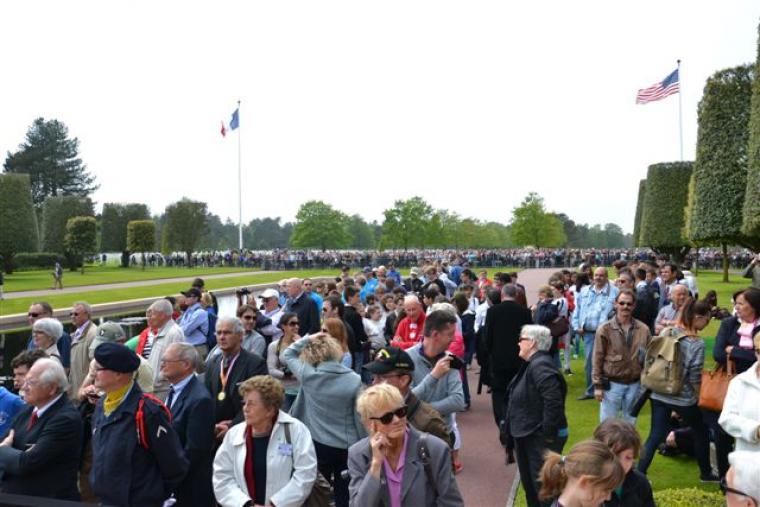 Crowds of people stand at Normandy Cemetery