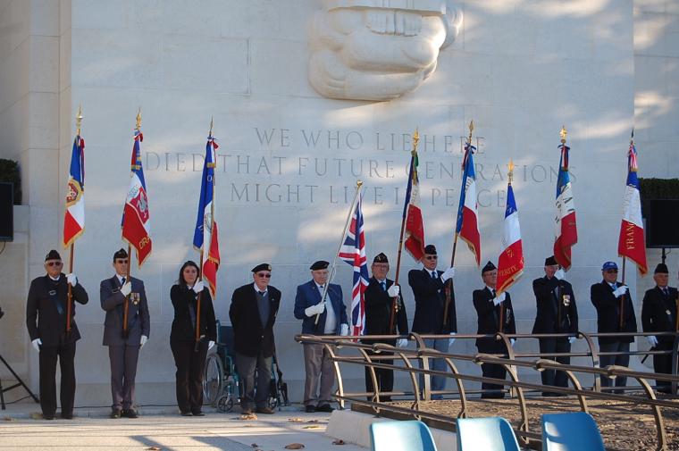 Participants stand in a row with flags in front of the chapel.