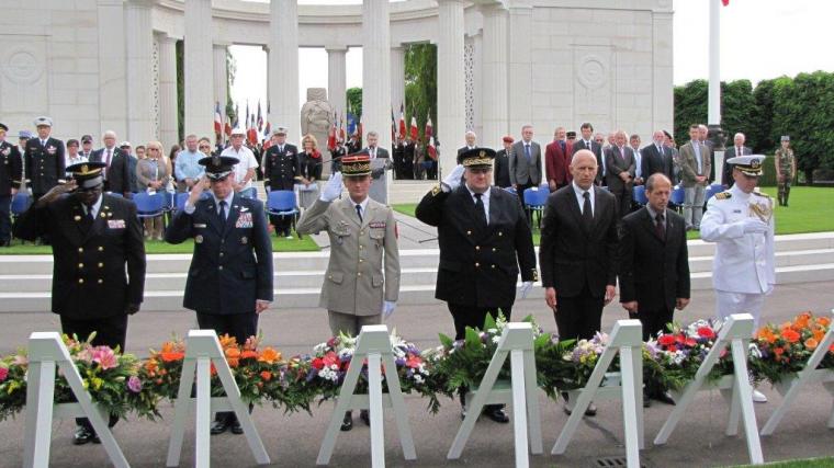 Men, some in uniform, stand saluting. 