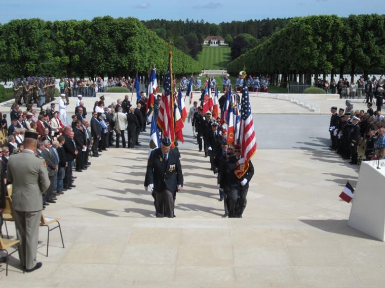 Men walk up the memorial stairs with flags.