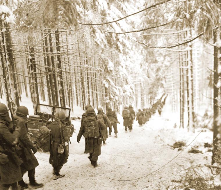 U.S. soldiers march to cut off the St.Vith-Houffalize road in Belgium.