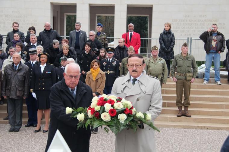 Two men carry a floral arrangement during the 2012 Veterans Day ceremony at Epinal American Cemetery. 