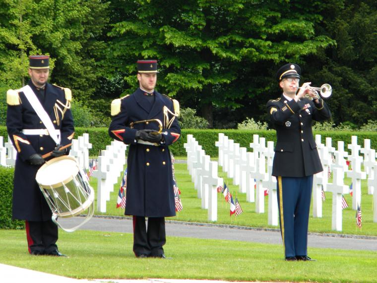 A U.S. military bugler plays, while standing in front of the marble headstones.