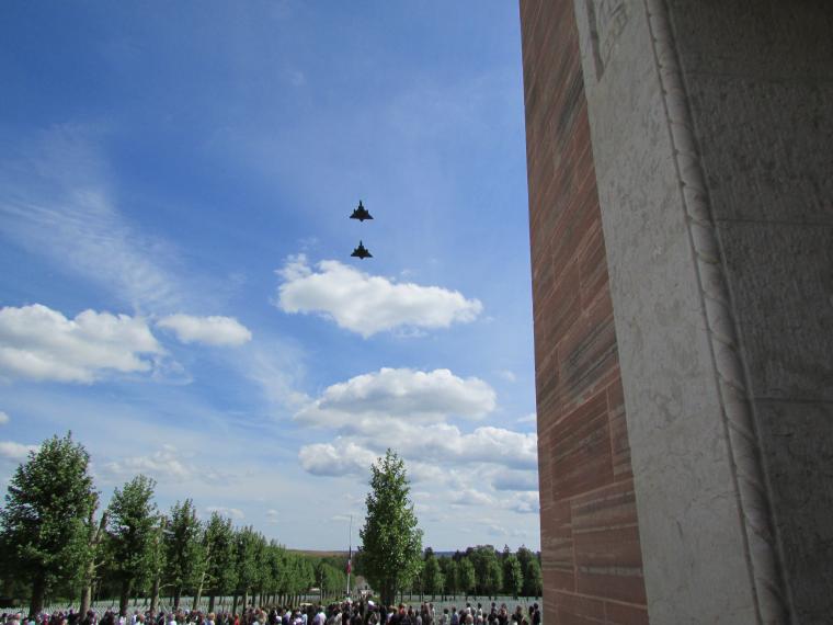 Two fighter jets fly over  the cemetery grounds. 