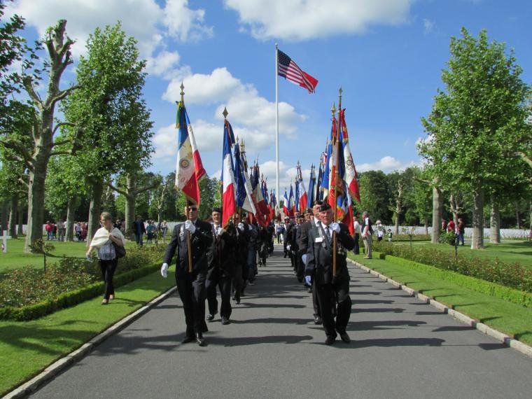 Men march with flags down a paved pathway. 