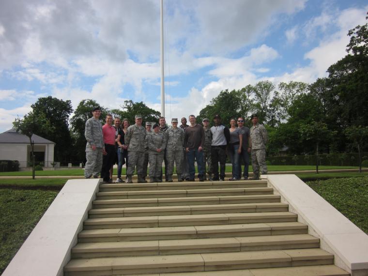Volunteers stand at base of flag pole. 