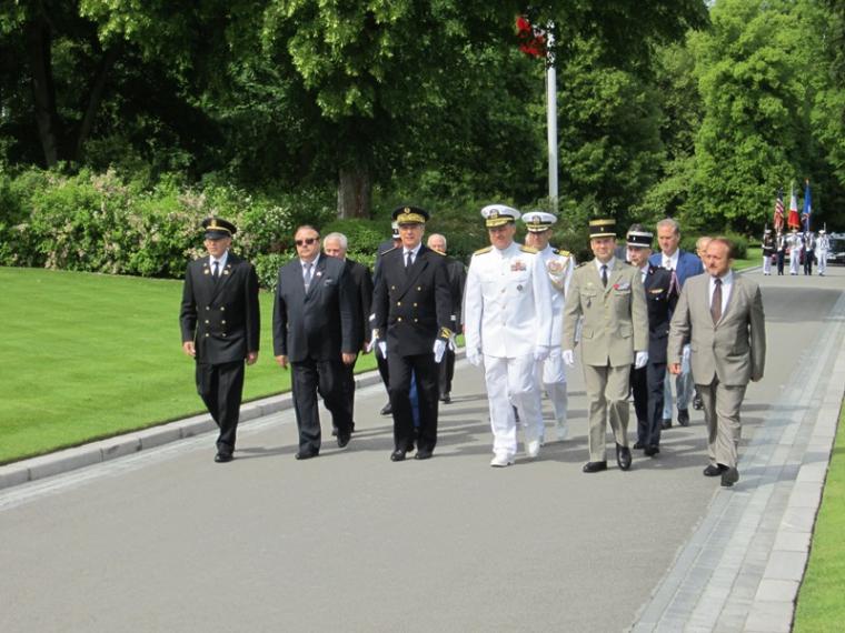 Men, some in uniforms, walk down a paved pathway. 