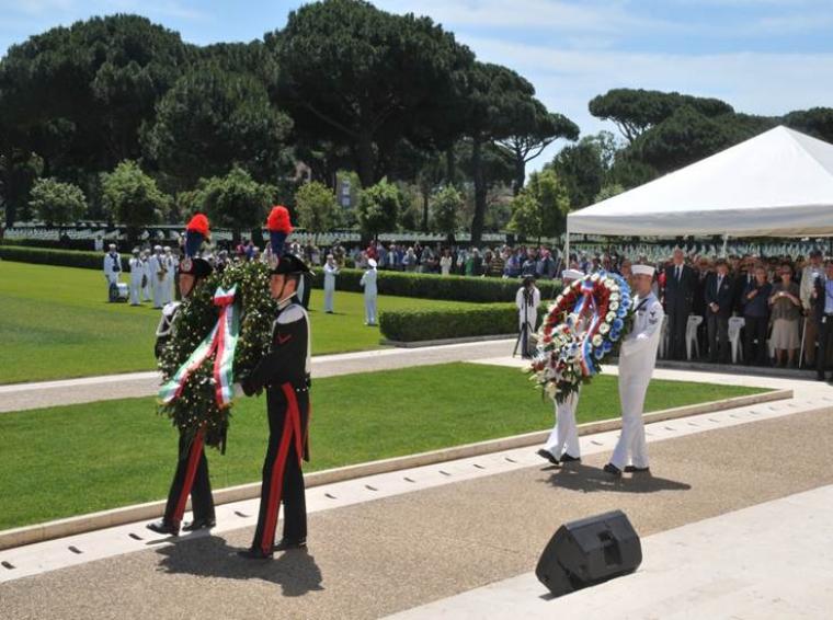 Members of the U.S. and Italian military walk with floral wreaths. 