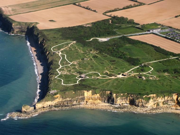 An aerial view of Pointe du Hoc shows the English Channel, the cliffs of the Pointe and the cratered ground.