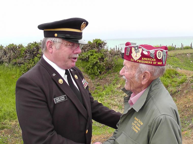 Normandy Cemetery Superintendent Hans Hooker greets a World War II veteran at Pointe du Hoc.