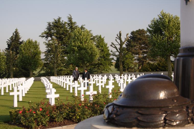 Visitors stand among the rows of white headstones at Somme American Cemetery.