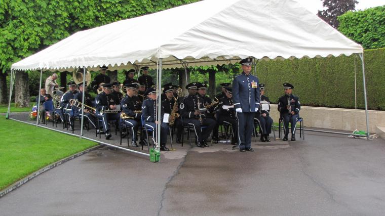 A U.S. Air Force Band sits under a tent, ready to perform in the ceremony. 