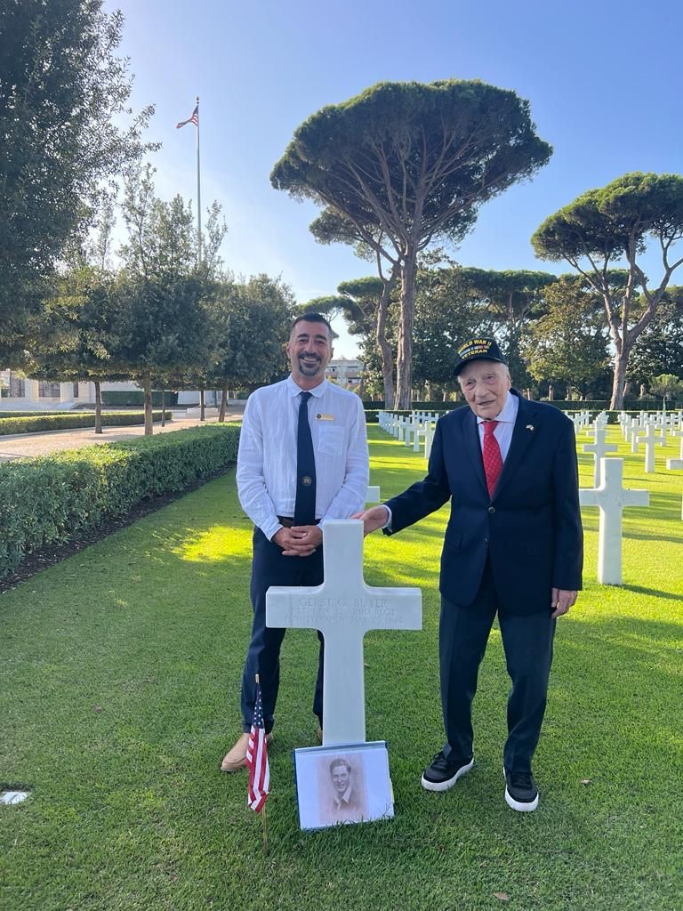 World War II veteran Dominick Critelli with an ABMC team member behind the headstone of one of his brothers in arms. Credits: ABMC.