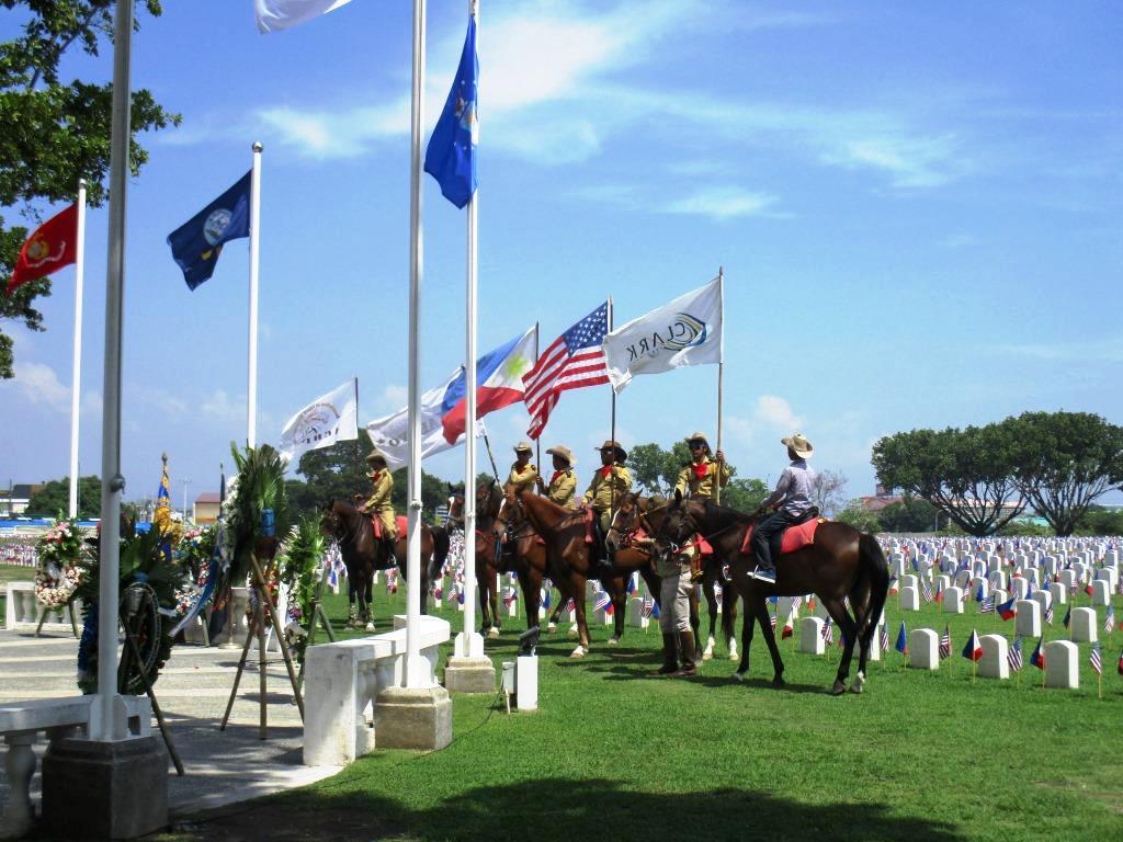Men on horses are between the ceremony area and the plot area.