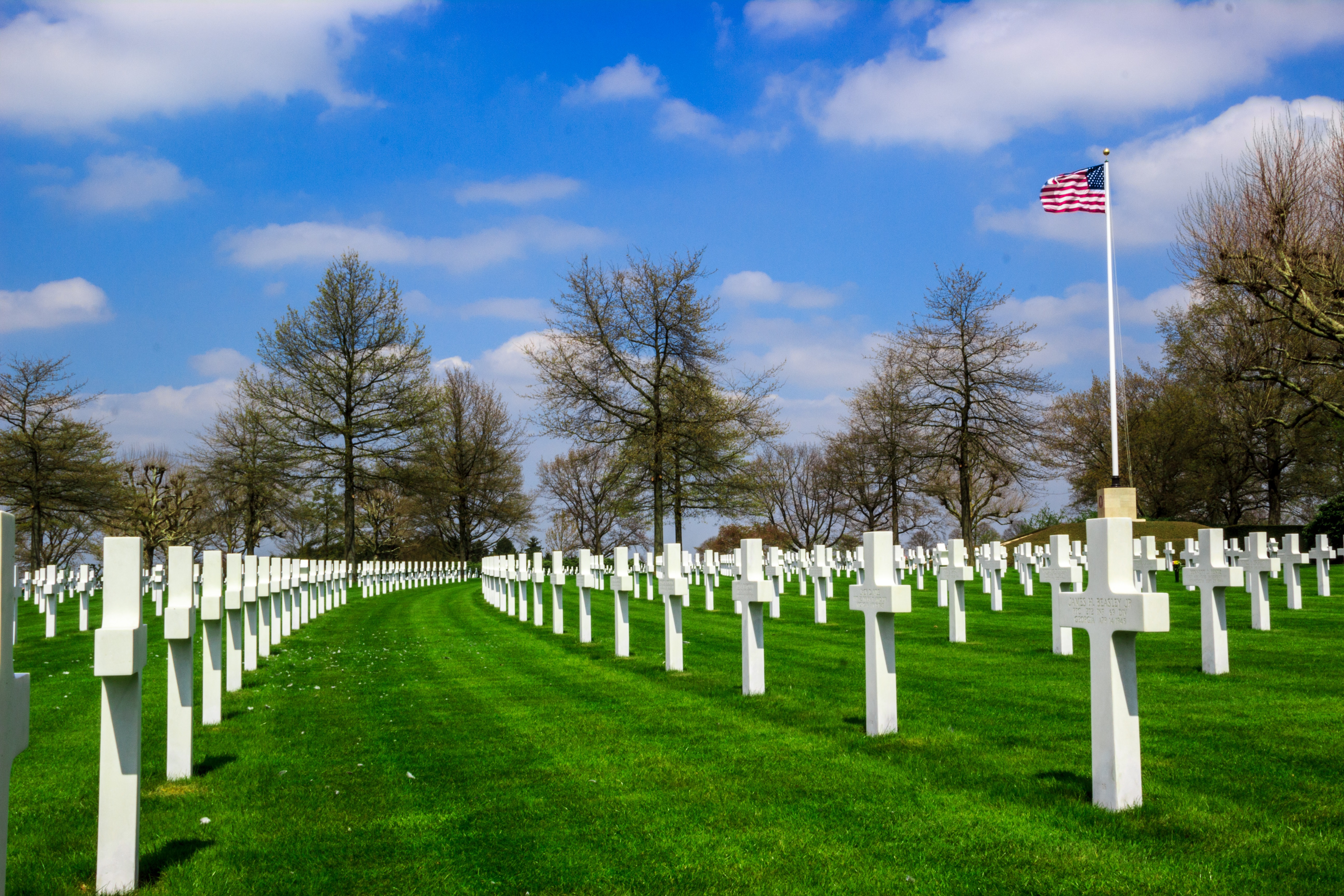 Grass, headstones, and flagpole are seen at Netherlands American Cemetery 