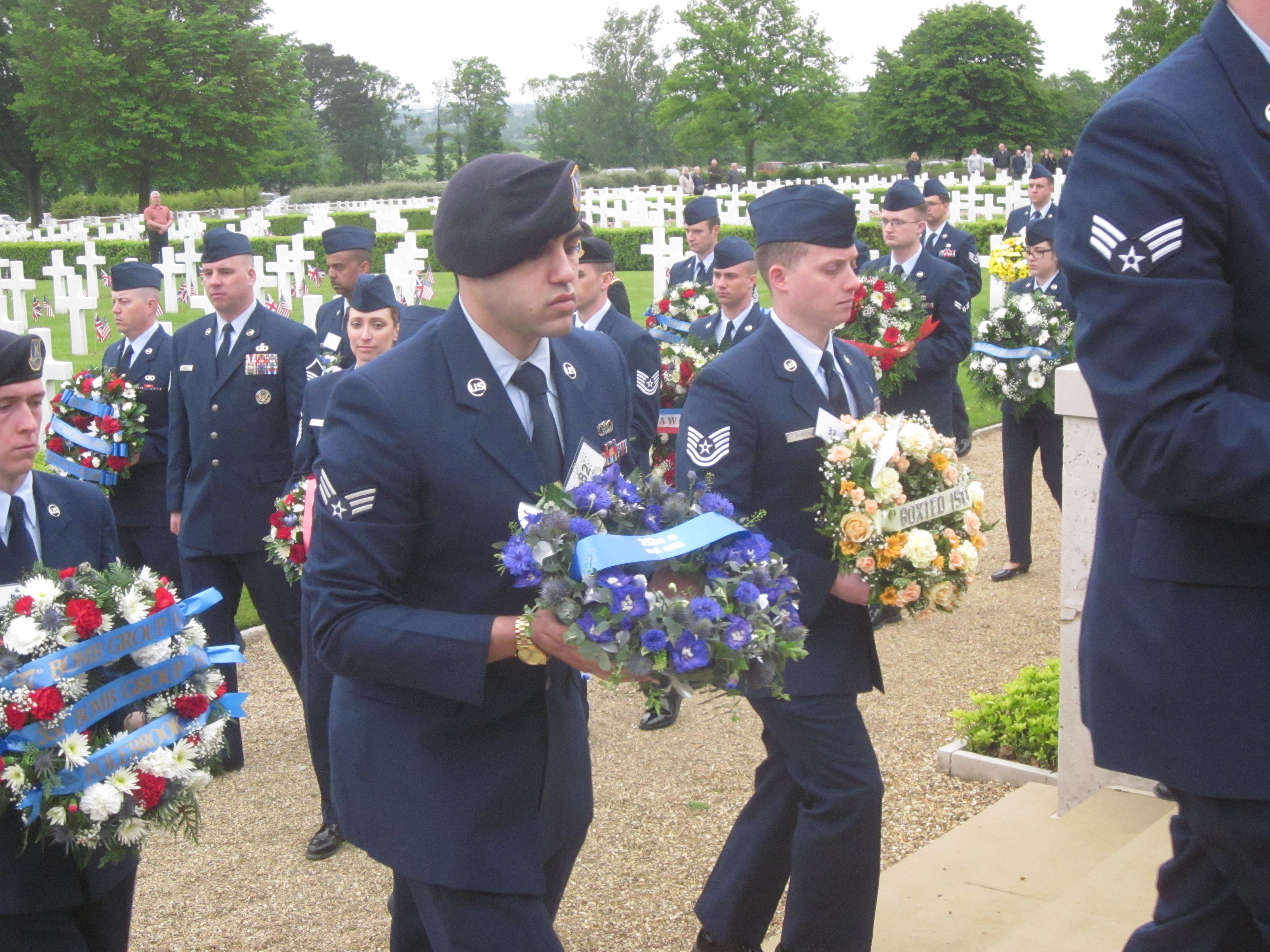 Members of the Air Force walk with small floral wreaths.