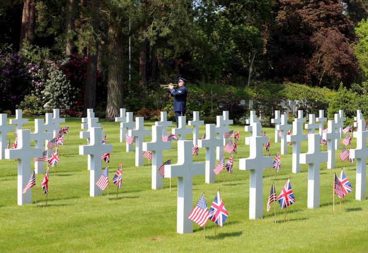 A man in uniform plays the bugle amongst the headstones. 